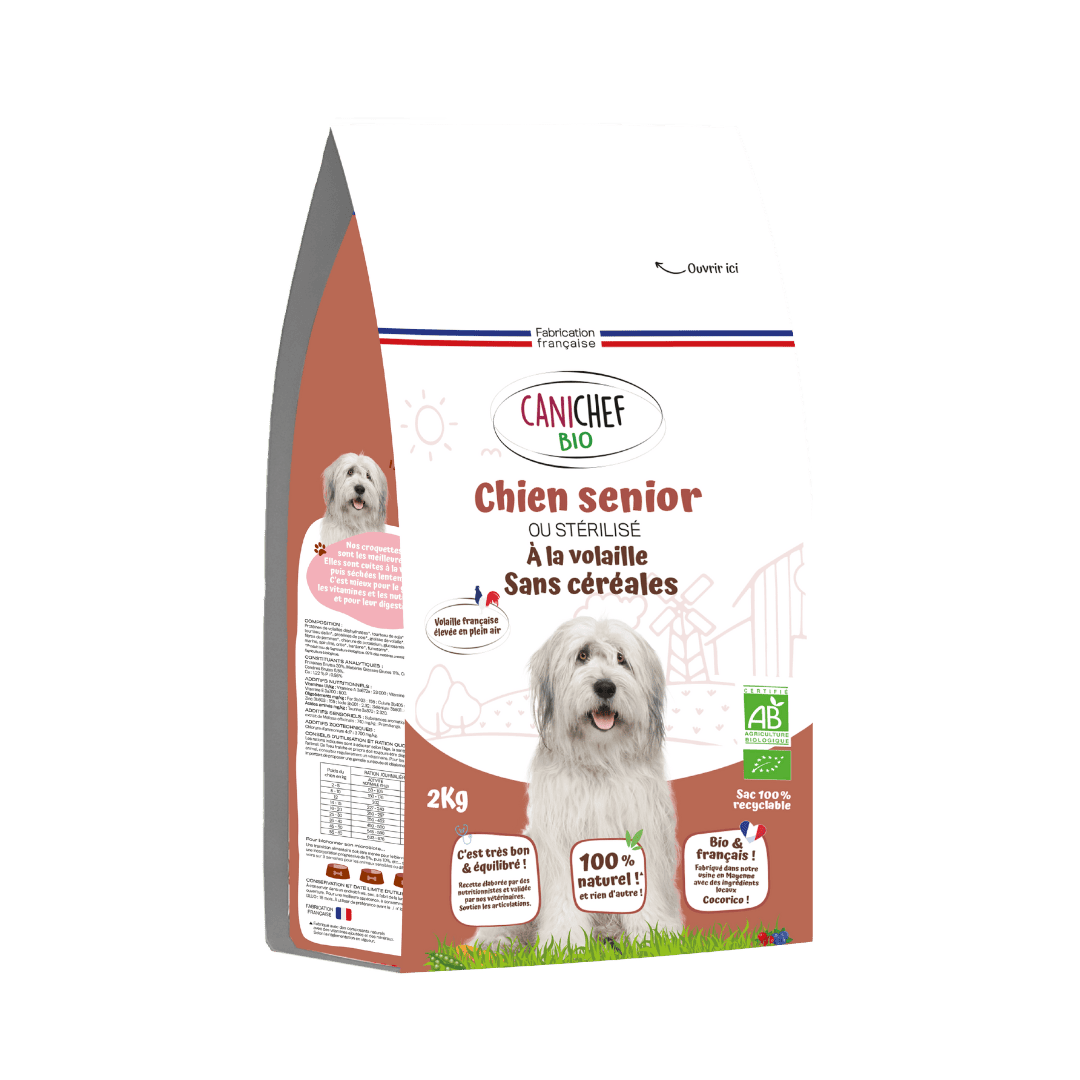 Un sac de croquettes sans céréales bio pour chien sénior est au centre de l’image. Le sac marron de 2 kg contient des croquettes naturelles saveur volaille. Le fond est blanc.