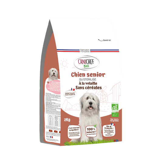 Un sac de croquettes sans céréales bio pour chien sénior est au centre de l’image. Le sac marron de 2 kg contient des croquettes naturelles saveur volaille. Le fond est blanc.